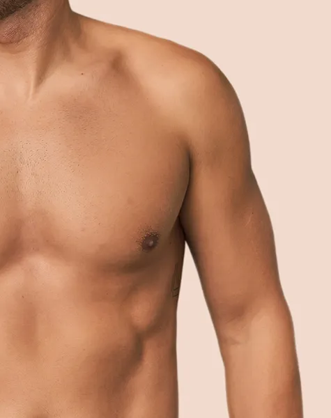 Grande plano do peitoral e ombro de um homem.