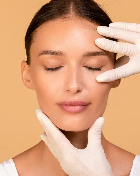 Mãos de um especialista a avaliar a testa e o rosto de uma paciente para um procedimento de lifting frontal.