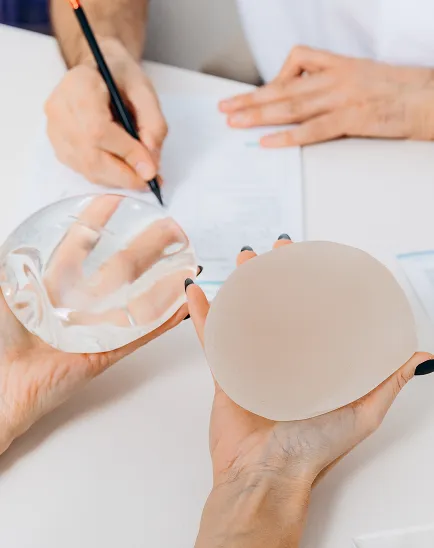 Paciente a escolher entre dois tipos de implantes mamários durante uma consulta com um cirurgião plástico.