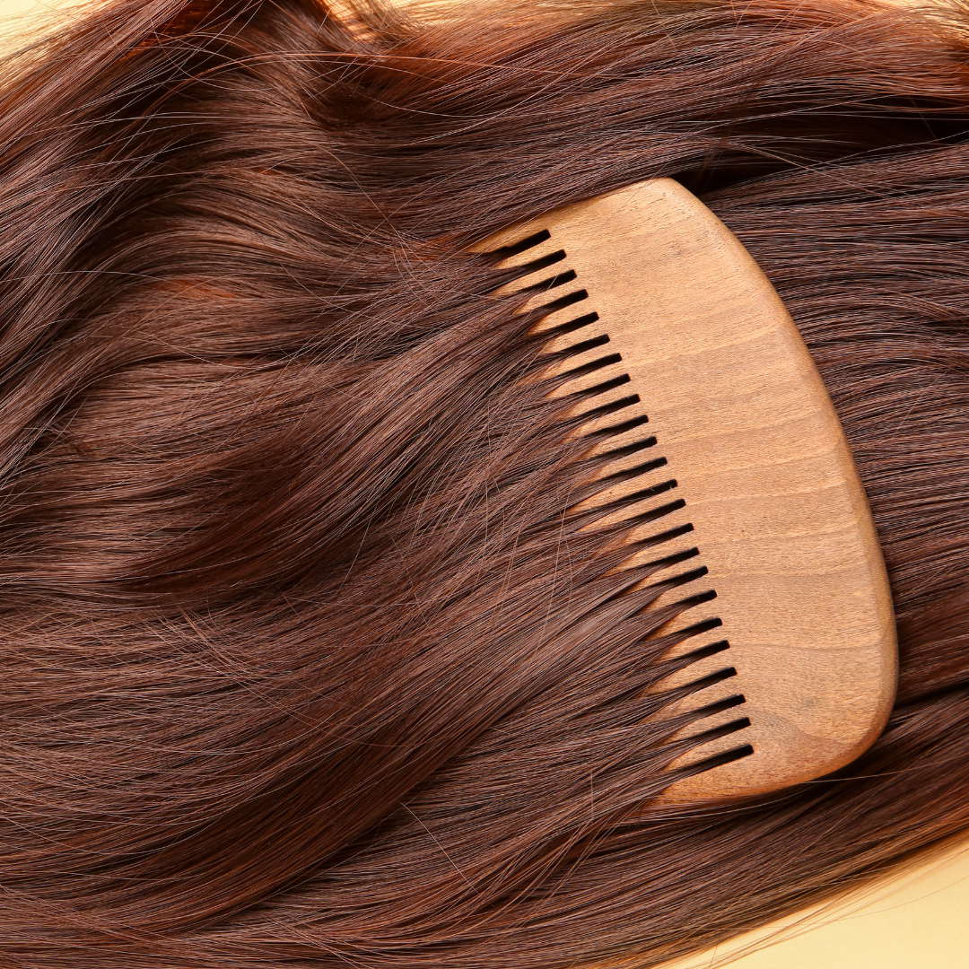 Cabelo comprido de mulher, de tom castanho, muito brilhante e cuidado, com um pente de madeira